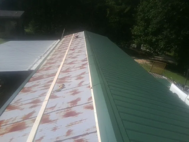 Old rusted panels beside newly installed green metal roofing — Wind Damage Roof Repair by Roofing Brothers in Rock Hall