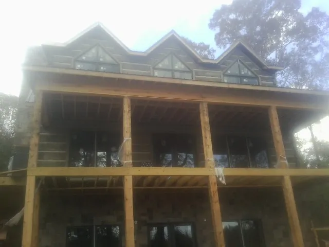 Dormers and porch framing on a large log home under construction — Roof Coating work by our crew in Rock Hall