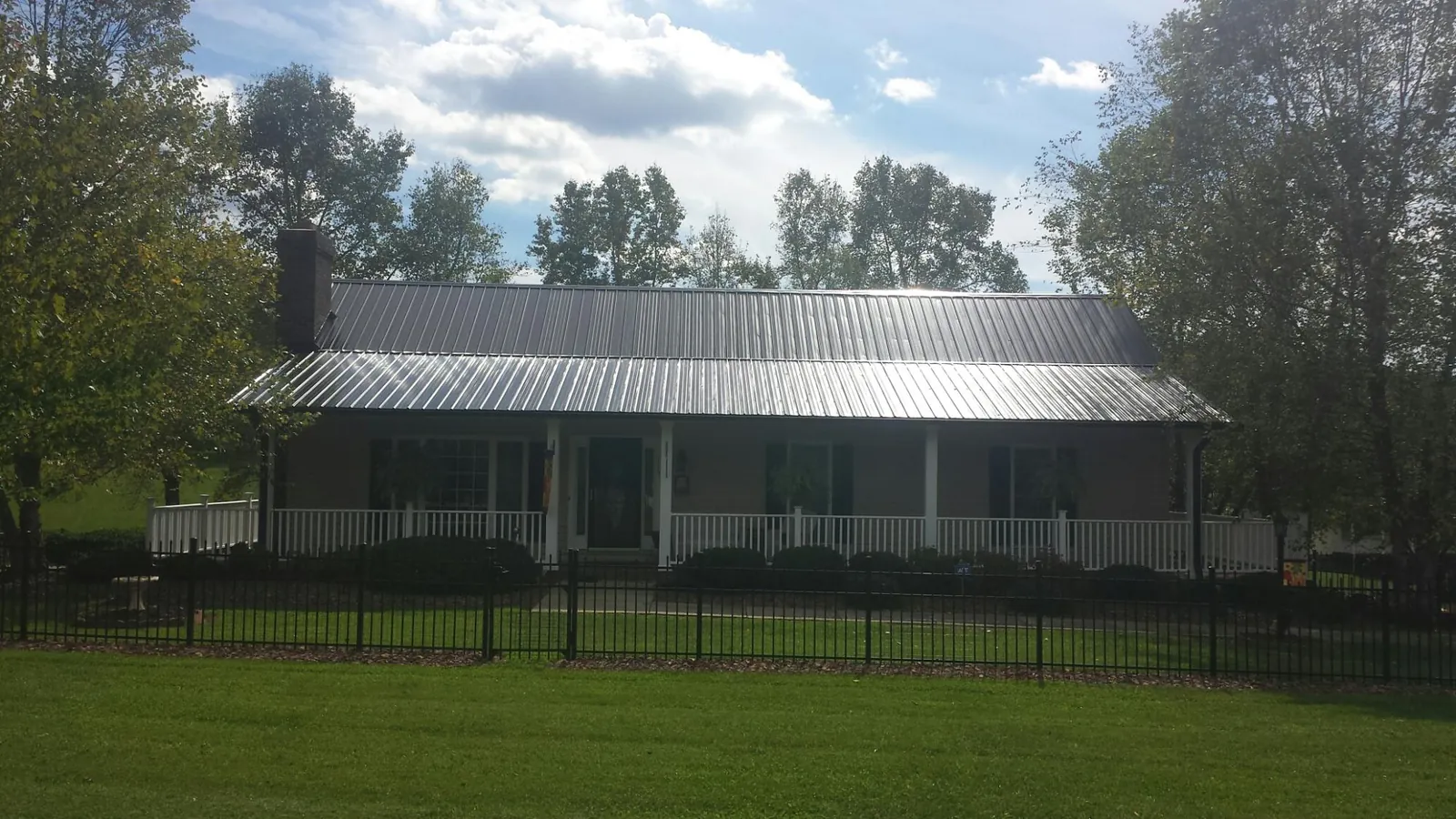 Gray metal roof on a brick ranch with a full width front porch — Gutter Guard Installation work by our crew in Rock Hall