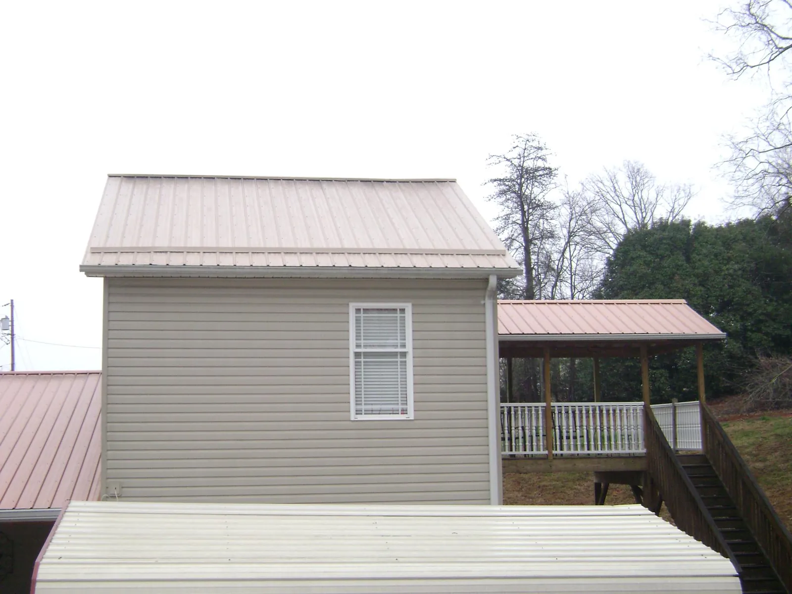 Tan metal roofs on a two story addition and attached porch, from a Roof Replacement job in Rock Hall