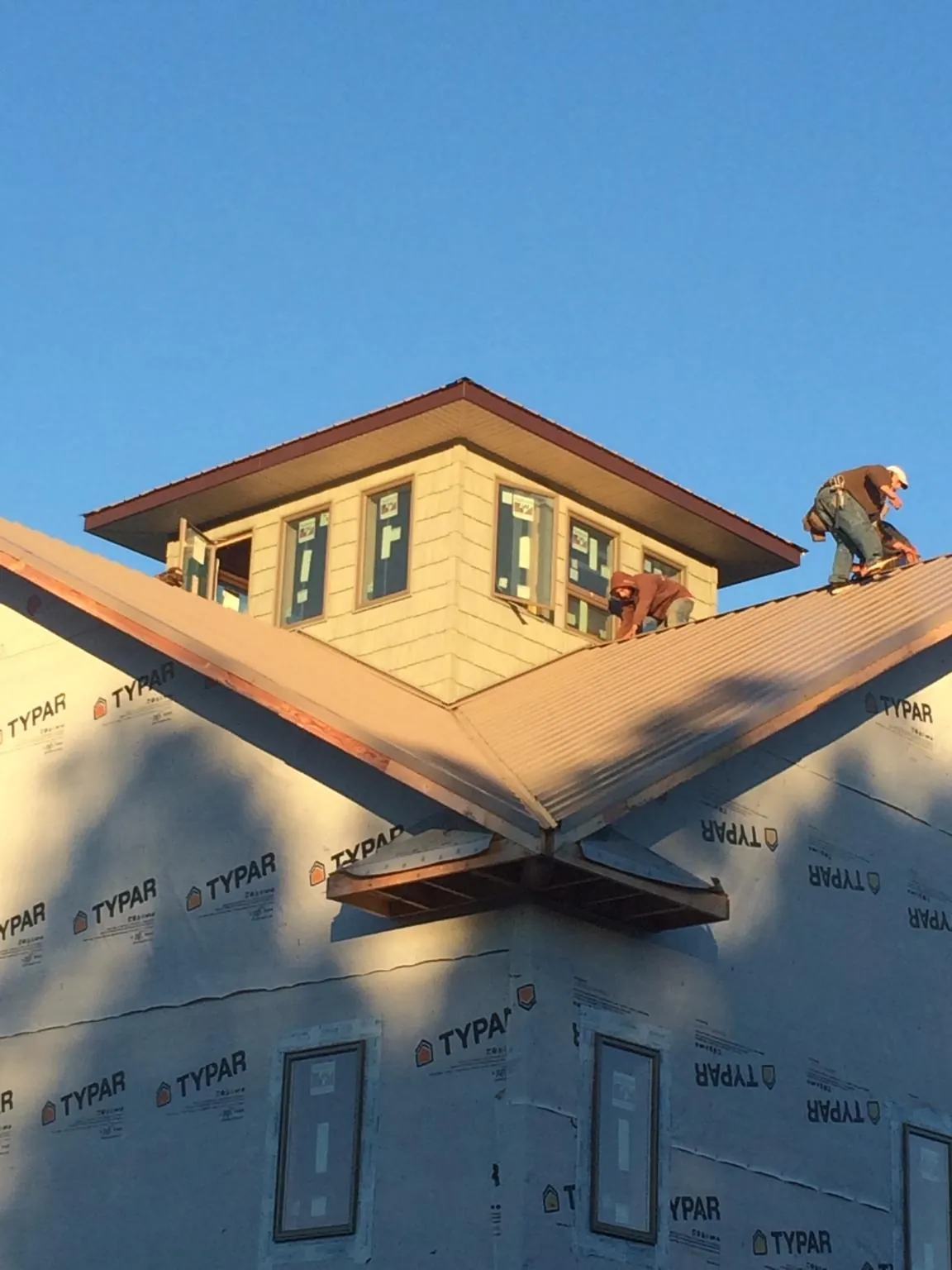 Roofers working around a rooftop cupola on a new metal roof at sunset — Roof Waterproofing in Rock Hall by Roofing Brothers